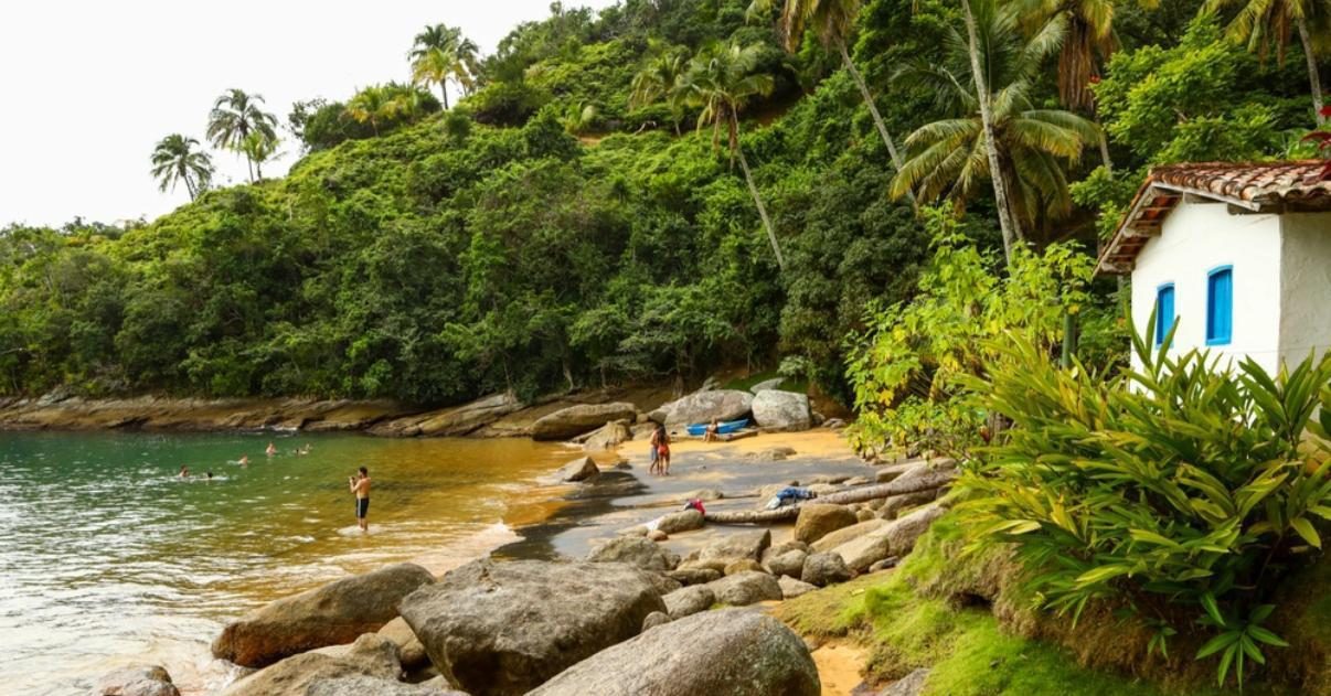 Praia com casa tradicional e costão rochoso