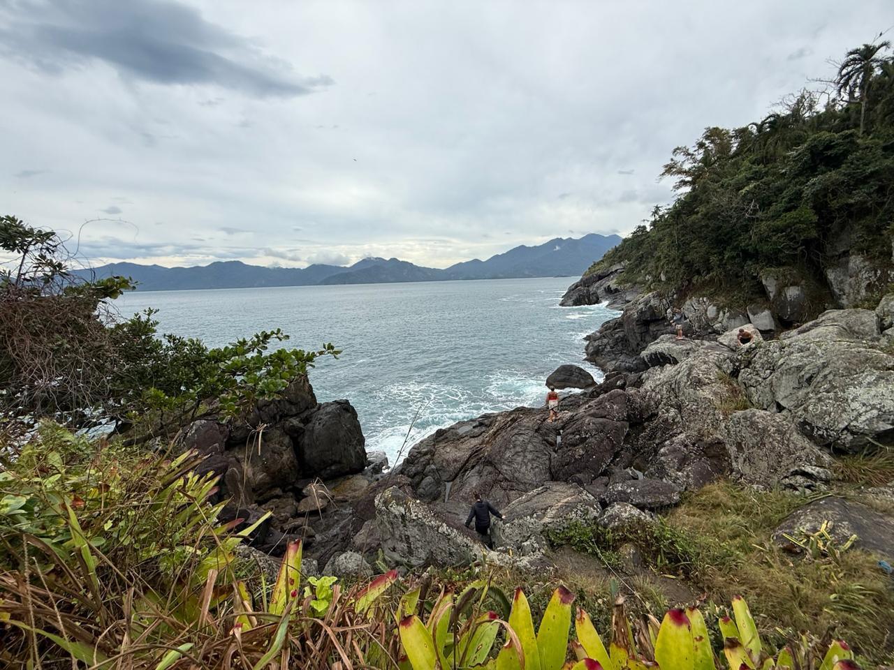 Trilha pelo costão rochoso com vista para o mar aberto e as montanhas de Ilhabela