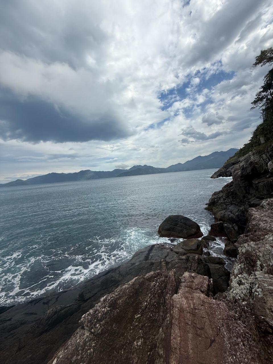 Vista dramática do costão rochoso de Ilhabela com mar agitado e céu nublado