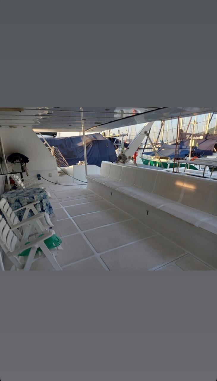 Interior do catamara com bancos brancos em U - deck espacoso para grupos grandes