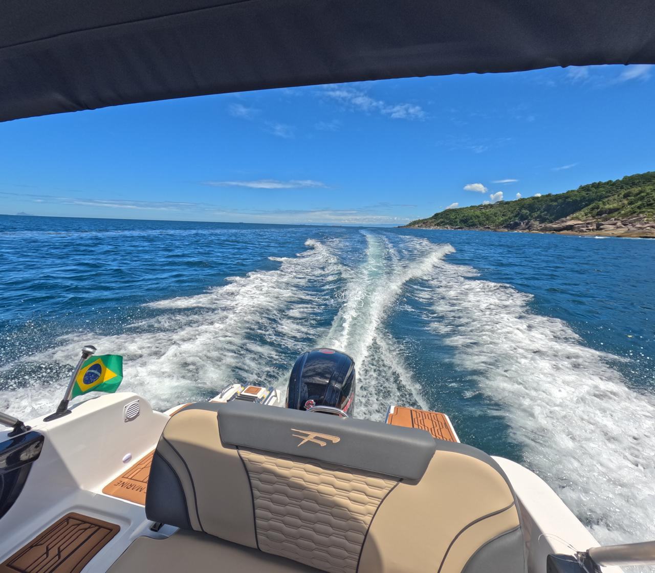 Vista da re do barco com wake, bandeira do Brasil e estofados em detalhe dourado