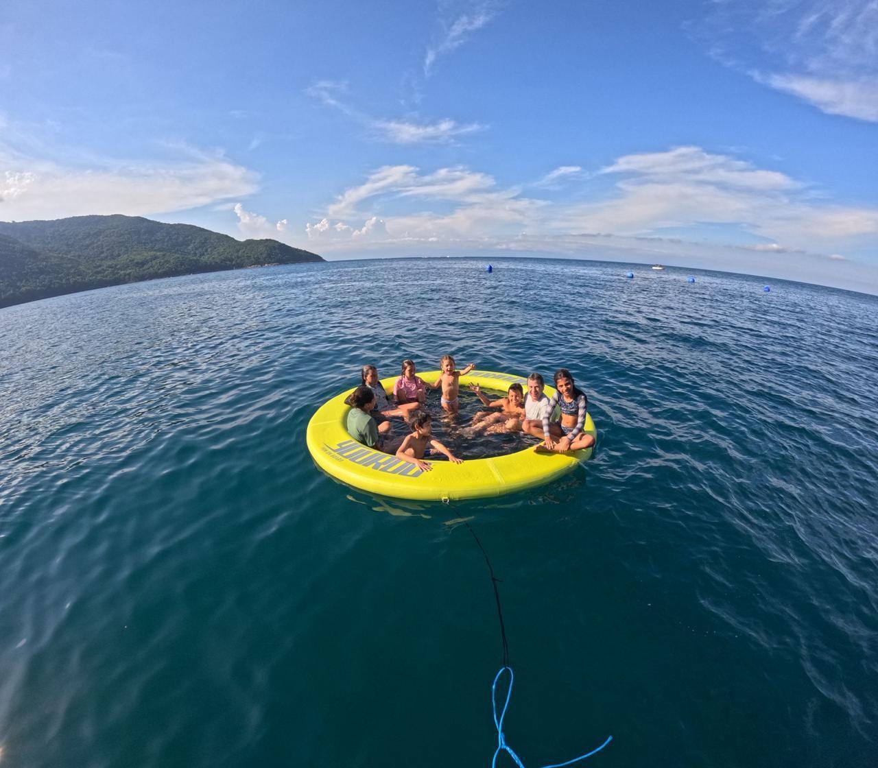 Grupo se divertindo na boia flutuante Yourou com Ilhabela ao fundo