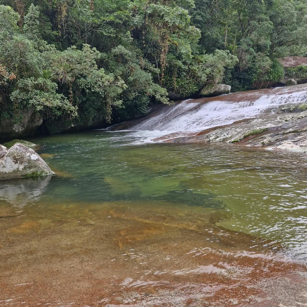 Poco natural de aguas verdes com cascata larga escorrendo pela laje na Cachoeira da Lage