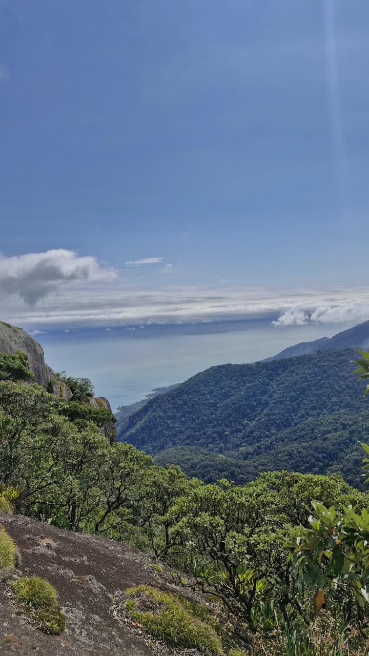Vista panoramica do topo do Pico do Baepi com nuvens abaixo e mar de Ilhabela